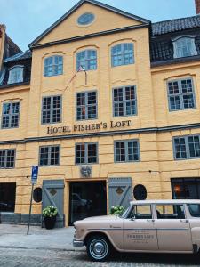 um carro velho está estacionado em frente a um hotel em Fisher's Loft Hotel em Lübeck