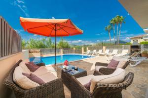 a patio with chairs and an umbrella and a pool at Villa JERONIMO Alcudia in Muro