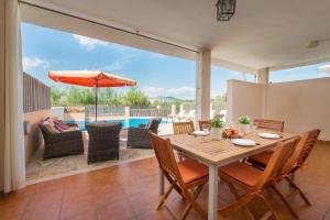 una sala da pranzo con tavolo, sedie e piscina di Villa JERONIMO Alcudia a Muro