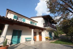 a white house with a porch and a balcony at Vila Salamander in Štanjel