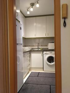 eine Küche mit weißen Schränken, einer Waschmaschine und einem Trockner in der Unterkunft Appartement à MALAGA in Málaga