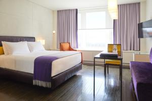 um quarto de hotel com uma cama, uma secretária e uma televisão em Hotel St Paul em Montréal