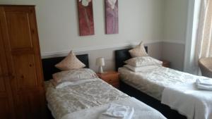 dos camas sentadas una al lado de la otra en una habitación en Beeches Guest House, en Dyce