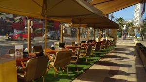 eine Reihe von Tischen und Stühlen mit Sonnenschirmen auf einem Gehweg in der Unterkunft Hotel Ankara in Viña del Mar