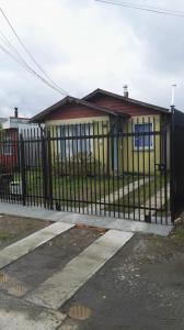 una cerca negra frente a una casa amarilla en Casa Gimar Austral, en Puerto Montt