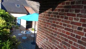 Chez Louise في Guise: وجود مظلة زرقاء جالسة بجانب جدار من الطوب