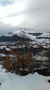 a mountain covered in snow with trees in the foreground at Casa Rural Los Robles in Valverde de los Arroyos