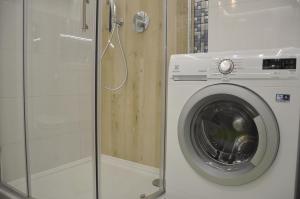 ビャウィストクにあるGolden Apartments - City Centrumのバスルーム(シャワー付)の洗濯機が備わります。