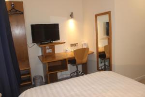 a bedroom with a bed and a desk with a television at Corona Hotel Rotherham Sheffield Meadowhall in Rotherham