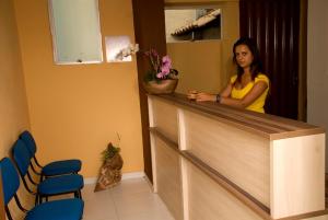 a woman standing at a counter in a waiting room at Orquídea Hotel in Viçosa