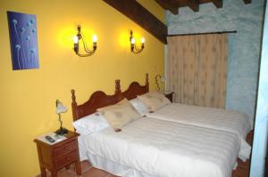 a bedroom with a large bed with white sheets at Casa Rural El Pedroso in Villar del Pedroso