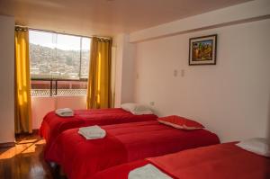 2 camas rojas en una habitación con ventana en Mayte Apartment, en Cusco