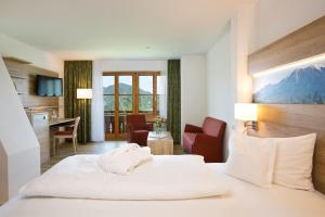 ein Hotelzimmer mit einem weißen Bett und einer Küche in der Unterkunft Ringhotel Nebelhornblick in Oberstdorf