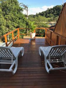 2 sillas blancas sentadas en una terraza de madera en Casa Linda Ilhabela, en Ilhabela