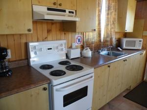 a kitchen with a white stove and a sink at Chalets Shipek in Les Escoumins