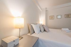 a white bedroom with a bed and a lamp at Syntagma Spa with Acropolis View in Athens