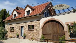 a house with a brown roof and a wooden garage at Gite La Fixoune in Voegtlinshoffen