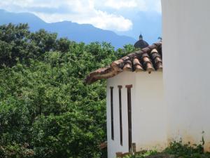 a white building with trees and mountains in the background at Casa Taller in Barichara
