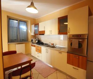 una cocina con armarios blancos, una mesa de madera y un tocador en Appartamento Vandero, en Alba 16 fotos más