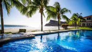 una piscina accanto a una spiaggia con palme di Villas Iguana A-14 Beachfront Condo a Iguana