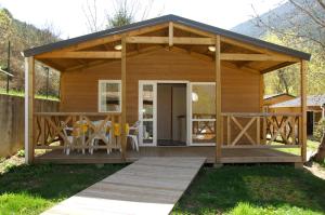 a wooden cabin with a wooden table and chairs at Camping La Ferme de Castellane in Castellane