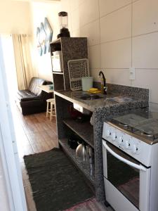 a kitchen with a stove top oven next to a living room at Casa do Nei in Bombinhas