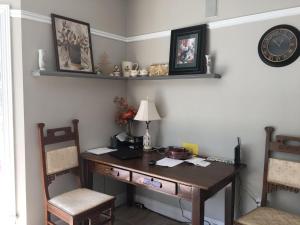 a desk with two chairs and a clock on a wall at Seaview White House in Stratford