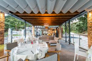a dining room with white tables and chairs on a patio at Aqua Oliva Resort Syvota in Syvota
