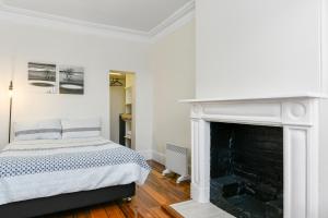 a white bedroom with a bed and a fireplace at Trinity Hill Apartments in Hobart