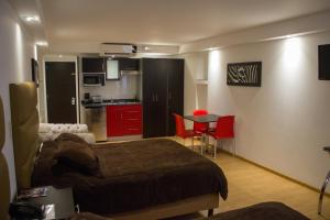 a bedroom with a bed and a kitchen with red cabinets at My Home Suites in Celaya