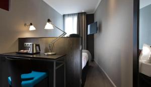 a hotel room with a desk with a lamp and a bed at Hôtel Garance in Paris