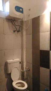 La salle de bains est pourvue de toilettes et d'un distributeur de papier sur le mur. dans l'établissement Ashta Lakshmi Tourist Home Stay, à Indore