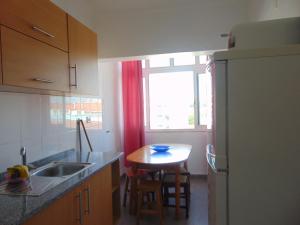 een keuken met een wastafel, een tafel en een raam bij BEM ME QUER 1 in Almada