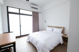 um quarto com uma cama branca e uma janela grande em LIANN Hotel em Taichung