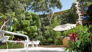 a patio with chairs and an umbrella and plants at kookaburra beach house coogee in Sydney +25 photos