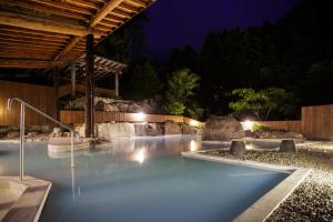 uma piscina iluminada à noite em Yufuin Onsen Tsukanoma em Yufu