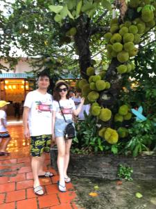 Ein Mann und eine Frau stehen neben einem Baum in der Unterkunft Minh Chau Beach Resort in Provinz Quang Ninh