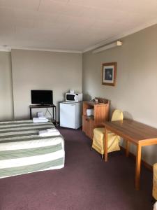 a hotel room with a bed and a desk and a table at Lilybrook Motel in Rangiora