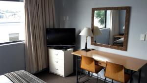 a hotel room with a desk with a television and a mirror at Off Broadway Motel in Auckland