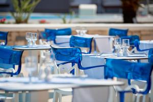 Mythos Palace Resort & Spa في جورجيوبوليس: مجموعة من الطاولات مع الكراسي الزرقاء وكؤوس النبيذ