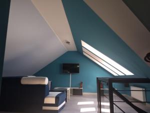 Cette chambre mansardée est dotée d'un mur bleu et d'une lucarne. dans l'établissement Apartament Sunny Day, à Polanica-Zdrój