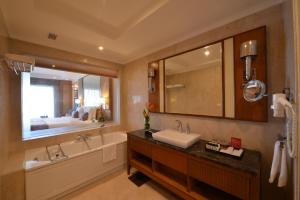 a bathroom with a sink and a tub and a mirror at Ramada Plaza Chennai in Chennai