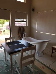 a bathroom with a tub and a table and a chair at Tzaneen White House Lodge in Tzaneen