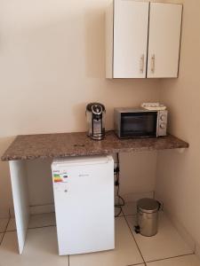 a kitchen with a counter with a microwave and a refrigerator at Tzaneen White House Lodge in Tzaneen
