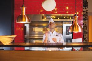 レーゲンスドルフにあるモーベンピック ホテル チューリッヒ レジェンズホフの台所に立つ料理人帽子の男