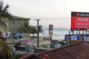 a person walking down a street next to the ocean at Lucky Beach Front Hostel in Hikkaduwa