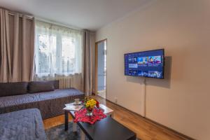 sala de estar con sofá y TV en la pared en Batory Apartament, en Chorzów