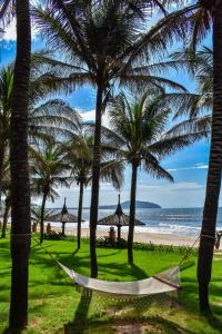 a hammock hanging between palm trees on a beach at Pandanus Resort in Mui Ne