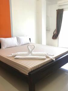 Una cama con dos cisnes encima. en Lert Sri Hotel en U Thong