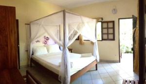 a bedroom with a white bed with a canopy at L' Hippocampe in Maroantsetra